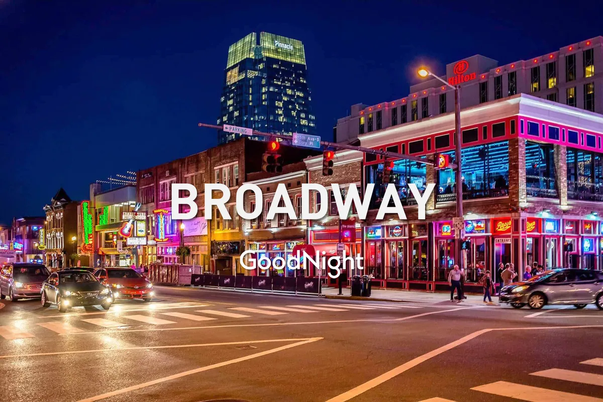 A vibrant and energetic street scene at night, featuring neon signs, a bustling crowd, and cars in motion. The image captures the lively atmosphere of Nashville’s nightlife and entertainment districts, with people out and about enjoying music, dining, and the city’s signature honky-tonk culture.