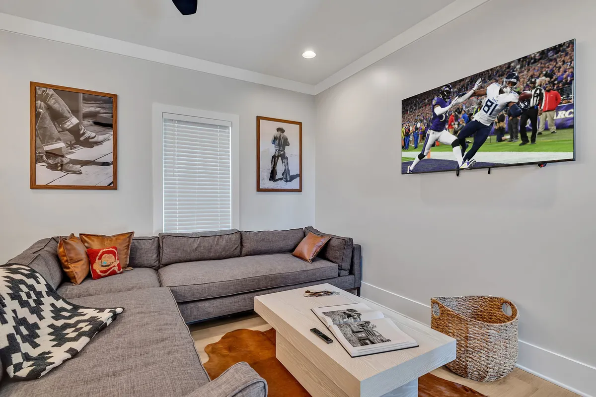 This image features a comfortable living area with a sofa, TV, coffee table, and wall art. The space is inviting and casual, with a welcoming atmosphere that hints at everyday relaxation and home comforts.